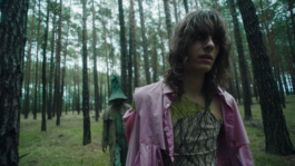 Standbild aus dem Musikvideo von der Band Der Ringer. Zwei Figuren, gespielt von Jakob Hersch und Jannik Morton Schneider, sind in einem dichten, alten Wald. Vorne im Bild ist Figur XY und ist erschöpft und wirkt geistesabwesend. Hinter denen läuft die Figur Fear mit Hut und Mantel in den Farben des Waldes und wirkt bedrohlich. 